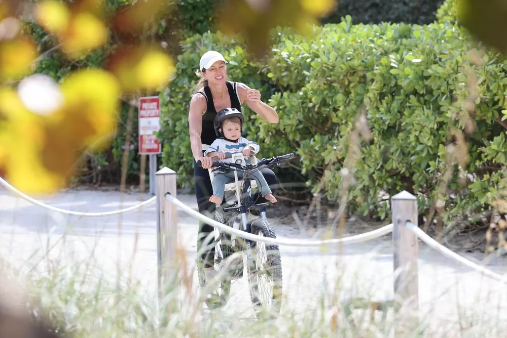 Жизель Бюндхен катает годовалого сына на велосипеде