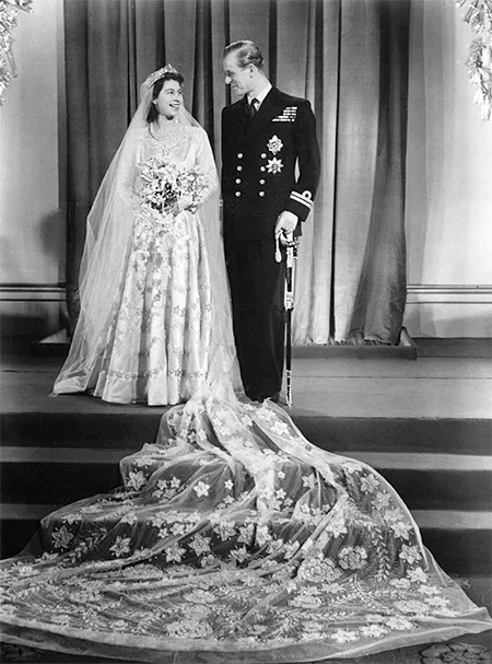 Свадьба Елизаветы и Филипа состоялась 20 ноября 1947 года в Вестминстерском аббатстве. На пошив наряда невесты правительство выделило 200 талонов на одежду (со времен войны королевство жило по карточной системе, которая была отменена только в 1954 году). Британский дизайнер Норман Хартнелл создал платье из сатина цвета слоновой кости, вдохновившись картиной «Весна» Боттичелли. Расшил его серебряной нитью, кристаллами и жемчугом. Наряд дополнял четырехметровый шлейф из тюля