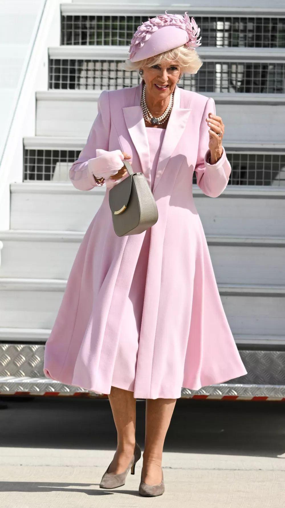 Королева Камилла - достойная ученица Елизаветы II. Прибыв во Францию, она спускалась по трапу в нежно-розовом костюме, который будет различим в толпе, в шляпке, в колготках, с маникюром натурального оттенка и сумочкой в левой руке.