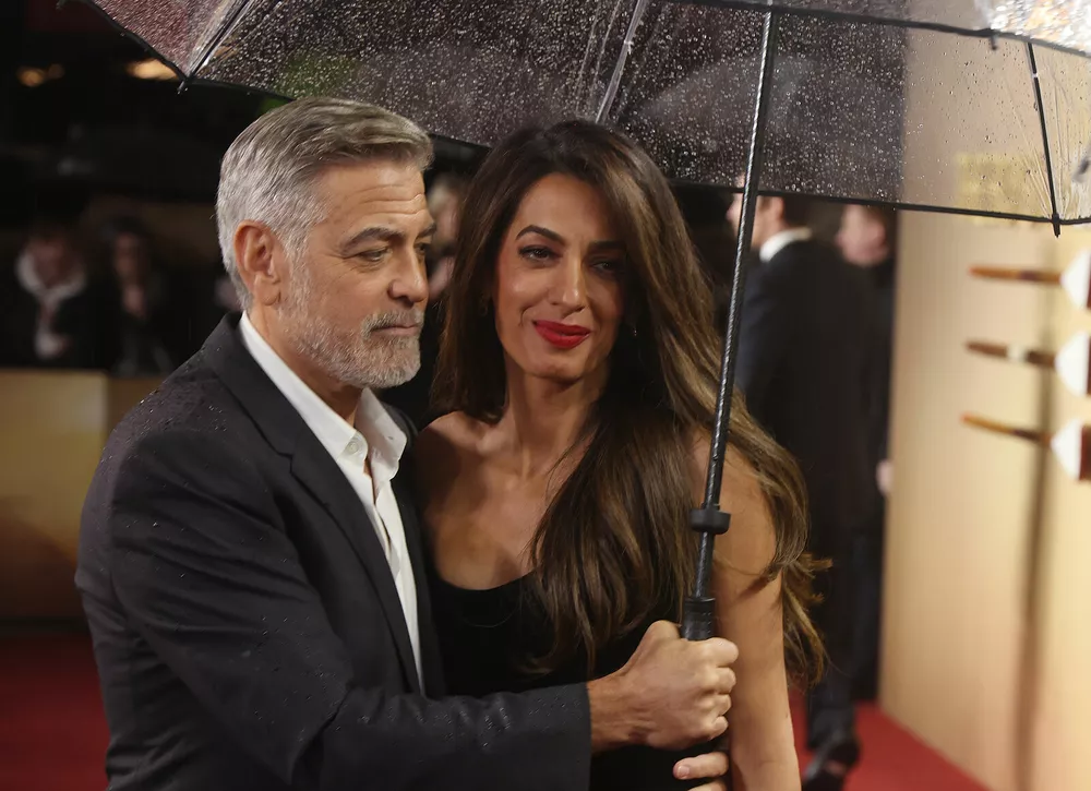 Заботливый муж: Джордж Клуни оберегает жену от дождя на светском мероприятии